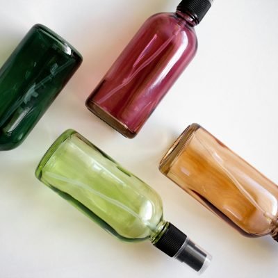 Four colorful spray bottles arranged on a white surface.